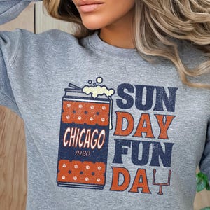 May include: Gray sweatshirt with a graphic of a beer can with the text "CHICAGO 1920" and the words "SUNDAY FUN DAY". The beer can has a red and white pattern.