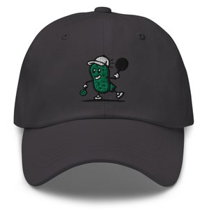 May include: A dark gray baseball cap with an embroidered green pickle character playing tennis. The pickle is wearing a white hat and holding a tennis racket.