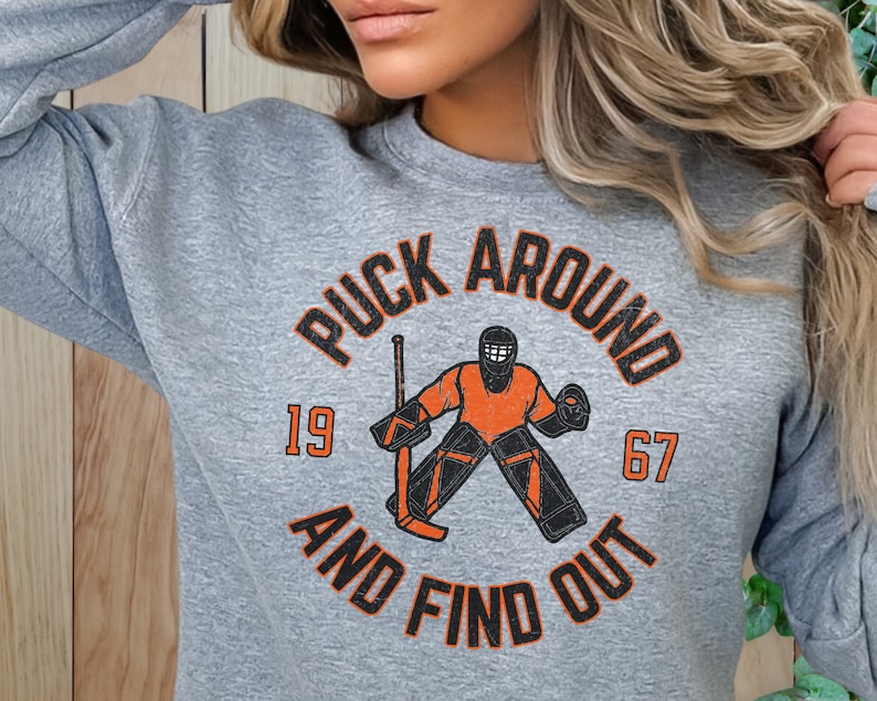 a woman wearing a puck around and find out sweatshirt