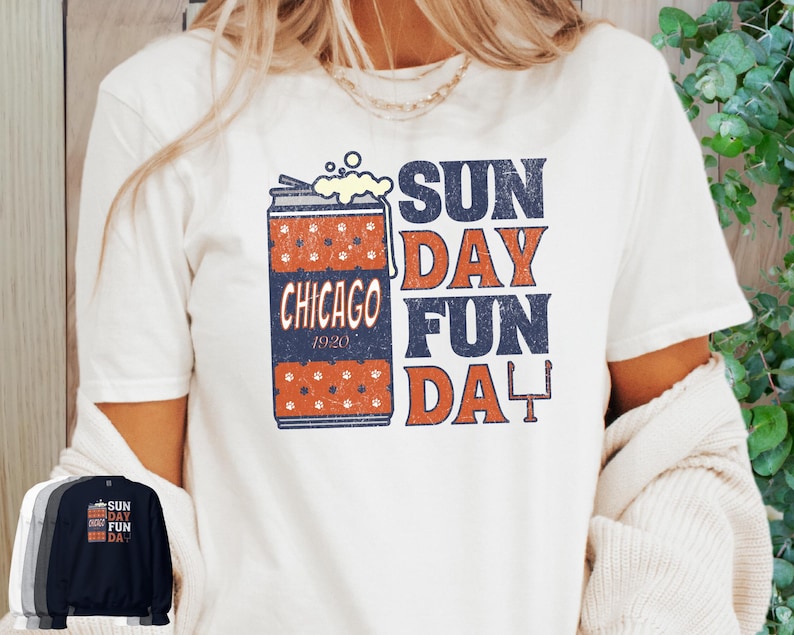 May include: Cream-colored t-shirt featuring a graphic design with a beer can illustration and the text "SUN DAY FUN DAY CHICAGO 1920". The design includes orange and navy blue elements. Several other shirt colors are shown below.