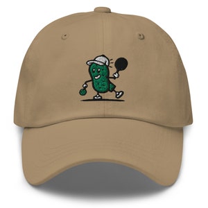 May include: A khaki baseball cap with an embroidered green pickle character wearing a white hat and holding a tennis racket. The pickle character is smiling and has a green tennis ball in its hand.
