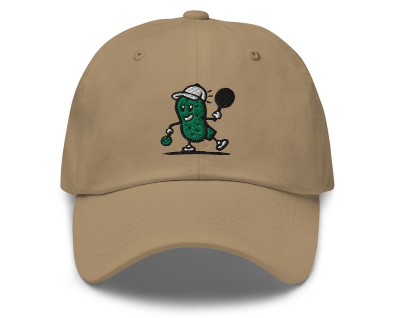 May include: A khaki baseball cap with an embroidered green pickle character wearing a white hat and holding a tennis racket. The pickle character is smiling and has a green tennis ball in its hand.