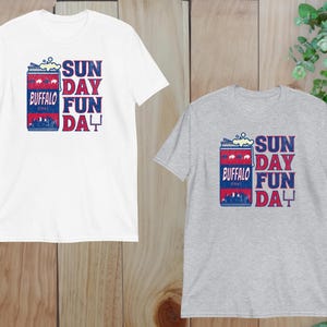 May include: Two t-shirts with a vintage-style graphic of a can of beer with the text "Buffalo" and "Sunday Fun Day". The t-shirt on the left is white and the t-shirt on the right is gray.