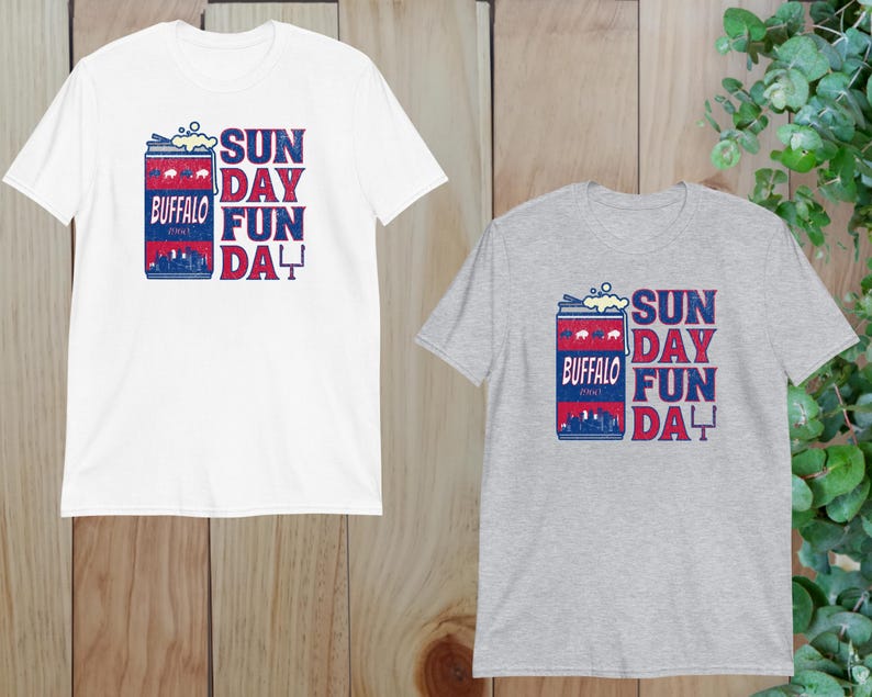 May include: Two t-shirts with a vintage-style graphic of a can of beer with the text "Buffalo" and "Sunday Fun Day". The t-shirt on the left is white and the t-shirt on the right is gray.