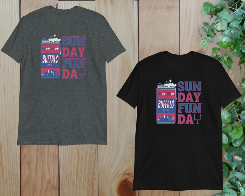 May include: Two t-shirts with a graphic of a can of Buffalo beer with the text "Sunday Fun Day" printed on them. The shirt on the left is dark gray and the shirt on the right is black.