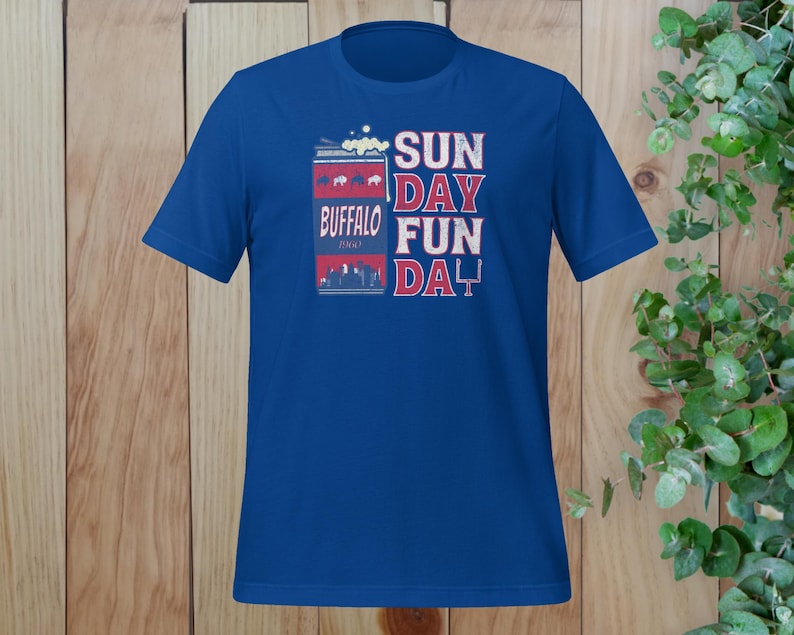 May include: A royal blue t-shirt with a graphic of a can of Buffalo beer and the text "SUN DAY FUN DA Y".