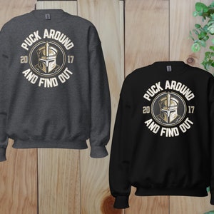a pair of sweatshirts on a wooden surface