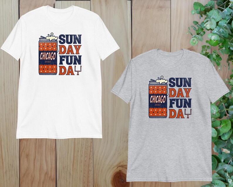 May include: Two short-sleeved t-shirts, one white and one gray, featuring a graphic design. The design includes a can with the text "Chicago", "Sunday Fun Day", and a football goalpost. The shirts are made of a soft material.
