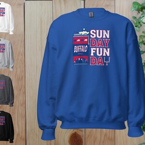 May include: A royal blue sweatshirt with a white and red graphic of a can of beer with the text "SUN DAY FUN DAY" and "BUFFALO" printed on it.