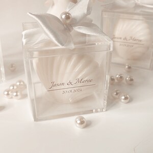 May include: Two clear acrylic boxes with white satin bows and pearl accents. Each box contains a white seashell-shaped soap with a personalised label. The label reads "Jason & Maree 20.01.2024".