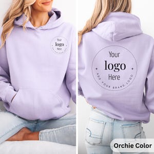 May include: A light purple hoodie with a front pocket and hood. The front and back of the hoodie feature a circular design with the text "Your logo Here" and "Add your brand logo". The hoodie is a solid color and is labeled "Orchie Color".