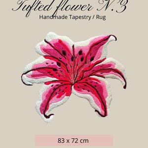 May include: A tufted flower tapestry rug featuring a lily design in shades of pink, red, and white with dark spots. The text reads Tufted flower N.3 Handmade Tapestry / Rug and 83 x 72 cm. Care instructions include vacuuming or using a mild carpet stain cleaner.