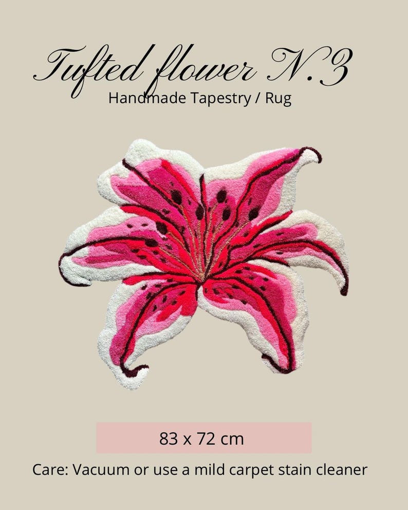 May include: A tufted flower tapestry rug featuring a lily design in shades of pink, red, and white with dark spots. The text reads Tufted flower N.3 Handmade Tapestry / Rug and 83 x 72 cm. Care instructions include vacuuming or using a mild carpet stain cleaner.