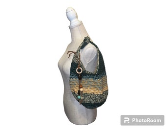 May include: A green and beige crocheted tote bag with wooden and blue beads hanging from the strap.