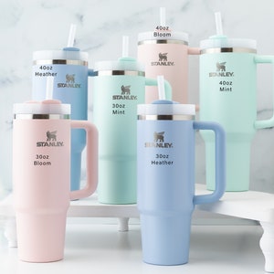 Stanley 40 oz and 30 oz tumblers in all the available colors shown together for size and color comparison. Heather, Mint and Bloom.
