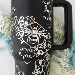 Stanley brand 40 oz tumbler in black with bumble bee and honeycomb design wrapped around the tumbler. Close up on bumble bee.