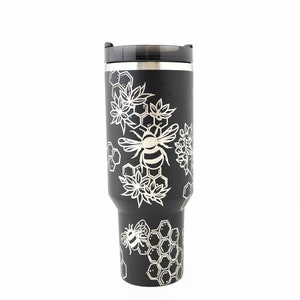 Stanley brand 40 oz tumbler in black with bumble bee and honeycomb design wrapped around the tumbler. Side view.