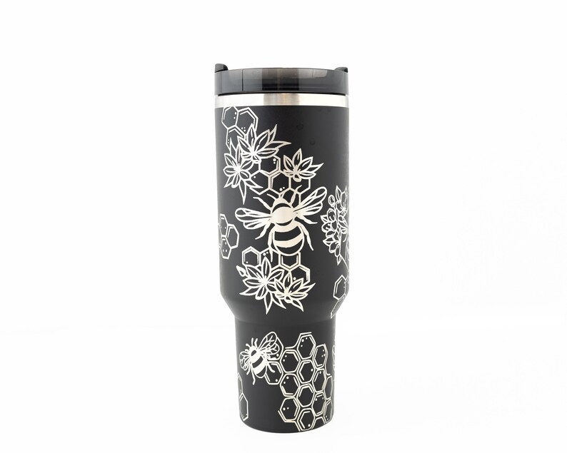 Stanley brand 40 oz tumbler in black with bumble bee and honeycomb design wrapped around the tumbler. Side view.