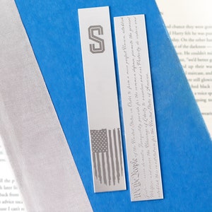 May include: Two silver bookmarks with an American flag design and the text "We the People of the United States in Order to form a more perfect Union, establish Justice, insure domestic Tranquility, provide for the common defense, promote the general Welfare, and secure the Blessings of Liberty to ourselves and our Posterity, do ordain and establish this Constitution for the United States of America."