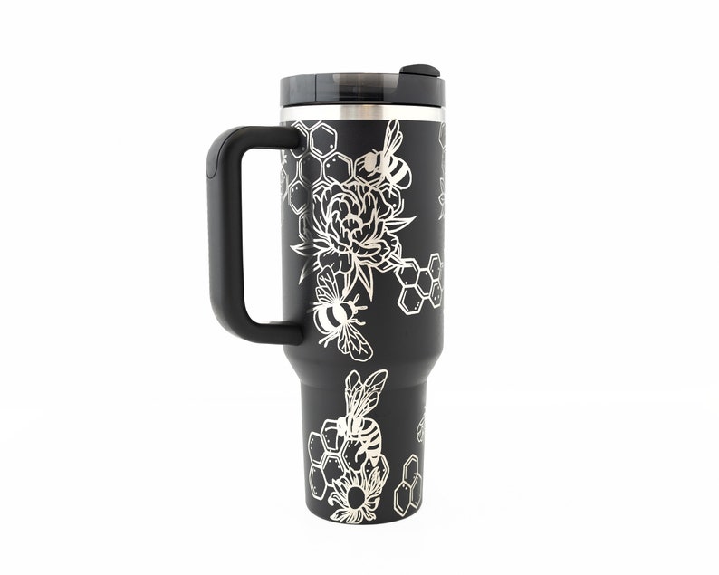 Stanley brand 40 oz tumbler in black with bumble bee and honeycomb design wrapped around the tumbler. Back view.