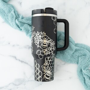 Stanley brand 40 oz tumbler in black with bumble bee and honeycomb design wrapped around the tumbler. Front view.