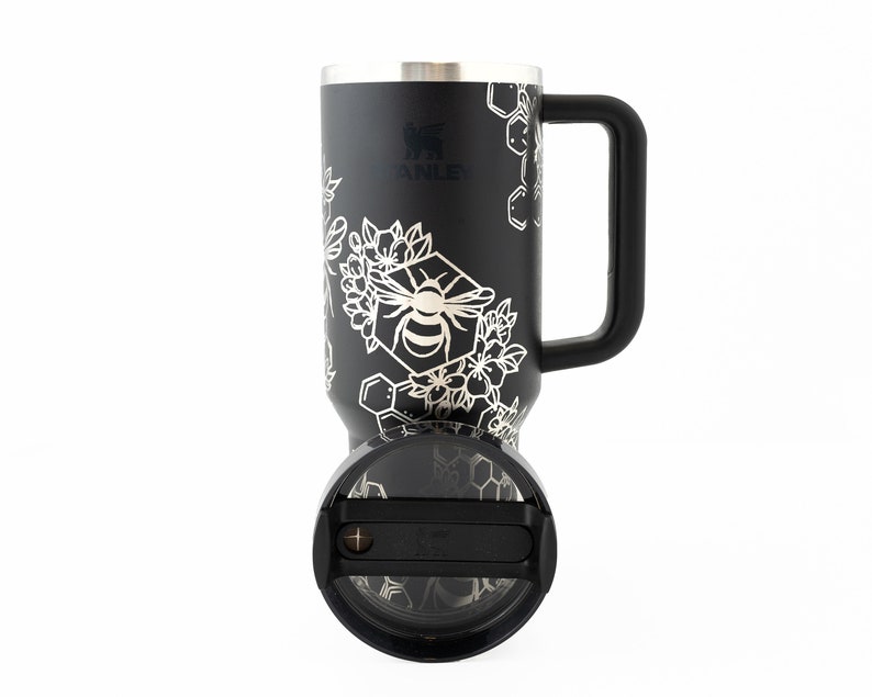 Stanley brand 40 oz tumbler in black with bumble bee and honeycomb design wrapped around the tumbler. Shown with lid facing front.