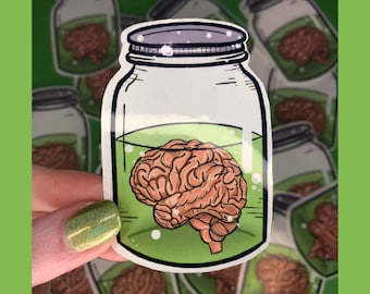 Könnte beinhalten: Ein Aufkleber mit einem Glasgefäß, gefüllt mit grüner Flüssigkeit und einem braunen menschlichen Gehirn. Der Aufkleber ist von anderen Aufklebern mit dem gleichen Design umgeben.