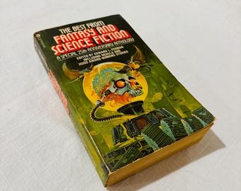 Puede incluir: Un libro de bolsillo titulado The Best from Fantasy and Science Fiction, A Special 25th Anniversary Anthology. La portada presenta un fondo verde con una ilustración central de un cráneo metálico, un orbe amarillo y criaturas voladoras.