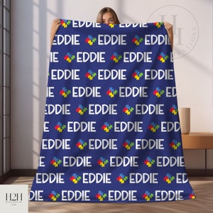 May include: A blue fleece blanket with a repeating pattern of the name "EDDIE" in white text and a colorful puzzle piece design.