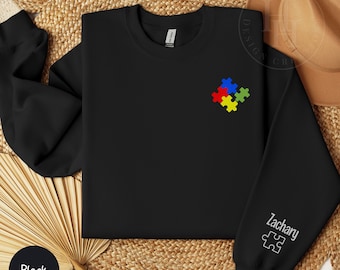 May include: Black sweatshirt with a colorful puzzle piece design on the front and the name "Zachary" with a puzzle piece on the sleeve.