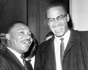 Może przedstawiać: Czarno-białe zdjęcie Martina Luthera Kinga Jr. i Malcolma X, którzy uściskują sobie dłonie. Obaj mężczyźni są w garniturach i krawatach. King uśmiecha się i ma przyjazny wyraz twarzy. X również się uśmiecha i wydaje się śmiać.
