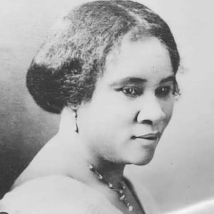 May include: Black and white portrait photograph of a woman with short, wavy hair. She is wearing a necklace and looking to the right.