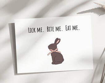 May include: A white card with the text "LICK ME. BITE ME. EAT ME." and a cartoon image of a brown chocolate bunny with a pink bow.