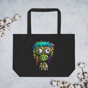 May include: Black tote bag with a colorful graphic of a green zombie with large eyes wearing glasses. The zombie has blue and green hair with colorful paint dripping down its face.