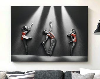 May include: A black and white 3D wall art piece depicting three dancers in a spotlight. The dancers are wearing red and black clothing. The art piece is a modern and abstract design.