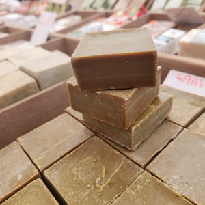 Puede incluir: Una pila de tres barras de jabón marrones, con una pila de barras de jabón similares en el fondo.