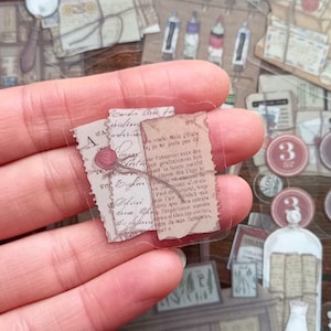 May include: A vintage-style clear sticker sheet with two translucent paper scraps featuring handwritten text in French. The text reads "Mais j'etais, jo ne jouis pas de, our l'observer avce des, rait généralement fort, at la haute société, blasés des lage le, potable el naerunt de, les indions un ale, Paul deusprat, trop, v Fair satisfait que, dire que mon entraia, l'expérience camine, civais si tien les oveiter, fonts de mes fantaisies, ps!"