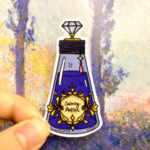 May include: A blue glass bottle with a diamond stopper and a gold label that reads "Calming Potion".