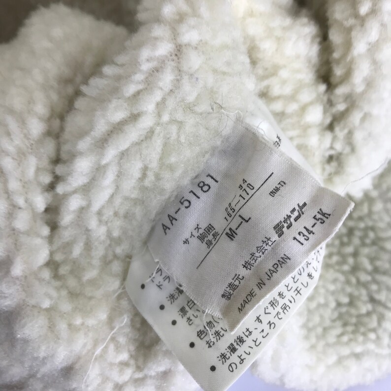 May include: White tag with black text. The tag has the text "AA-5181", "Size", "Chest", "Height", "34", "165-170", "M-L", "(NM-T)", "Manufacturer", "株式会社 デサワー", "Made in Japan", "134-5K".
