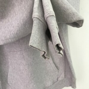 May include: A gray hooded sweatshirt with a pocket. The sweatshirt is folded and the sleeves are rolled up.
