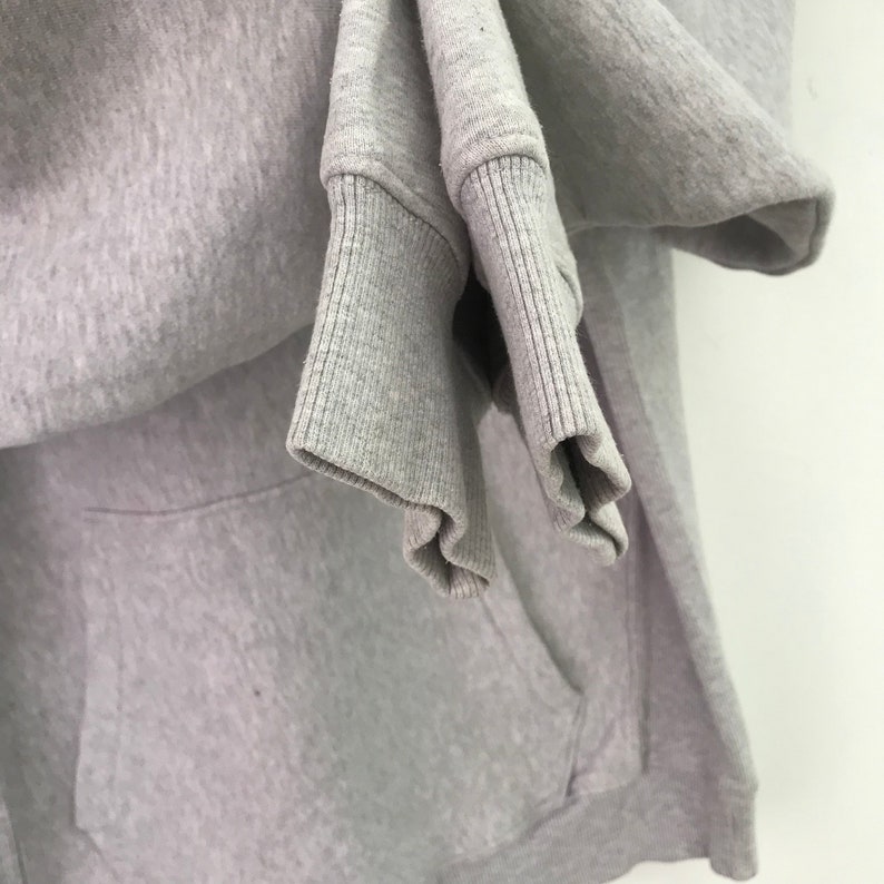 May include: A gray hooded sweatshirt with a pocket. The sweatshirt is folded and the sleeves are rolled up.