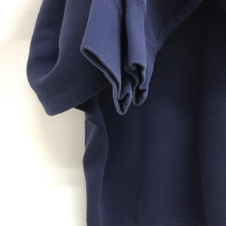 May include: A close-up of the navy blue sleeve of a sweatshirt. The fabric is soft and thick, with a slightly textured surface.