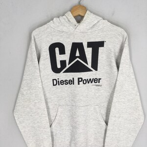 Puede incluir: Una sudadera con capucha de manga larga en color gris jaspeado claro que presenta un gran logotipo CAT negro impreso en el pecho con el texto Diesel Power debajo. La prenda incluye un bolsillo tipo canguro y capucha con cord&oacute;n.