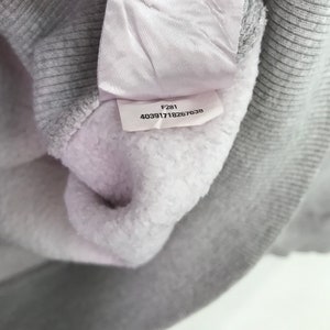 May include: A white tag with the text "F281 403917118267638" on a gray sweatshirt.