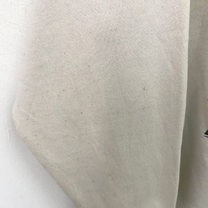 May include: Close-up of a white sweatshirt with a slightly textured surface. The fabric has a few small brown spots.