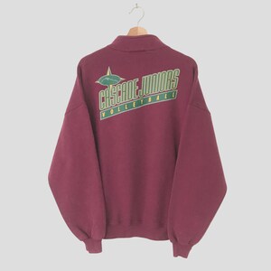 Puede incluir: Una sudadera color burdeos con un gráfico verde y amarillo en la espalda que dice "CASCADE JUNIORS VOLLEYBALL".