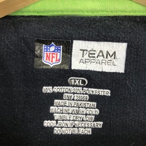 Puede incluir: Una camiseta polo negra NFL Team Apparel talla 1XL con cuello verde. La camiseta est&aacute; hecha de 80% algod&oacute;n y 20% poli&eacute;ster. Las instrucciones de cuidado son: Lavar a m&aacute;quina con agua fr&iacute;a, secar en secadora a baja temperatura, planchar a baja temperatura si es necesario, no usar lej&iacute;a.