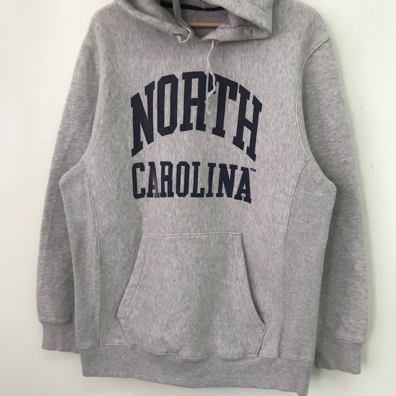 May include: Gray hooded sweatshirt with a navy blue "NORTH CAROLINA" logo printed on the front.