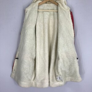 May include: Red and black hooded jacket with a white fleece lining. The jacket has a zipper closure and two pockets.