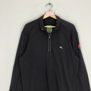 Peut inclure: Sweat-shirt noir &agrave; fermeture &eacute;clair quart avec un petit logo de dauphin brod&eacute; sur la poitrine gauche et un patch rouge avec un logo blanc sur la manche droite. Le sweat-shirt a une fermeture &eacute;clair rouge et une bordure rouge autour du col.